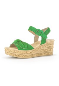 Sandale à talon compensé en daim vert avec un design à l'avant noué, une sangle de cheville ajustable et une plateforme texturée couleur beige liège.