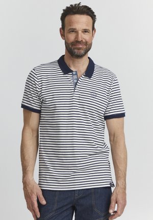 Camisa polo a rayas con cuello y acentos en navy, con rayas horizontales en blanco y navy, dos botones y un pequeño logo en el lado izquierdo.