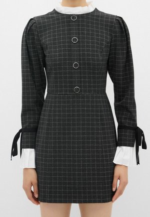 Ciemnoszara sukienka w kratę z długimi bufkami, okrągłymi guzikami z przodu, białymi falbankowymi mankietami i kołnierzykiem oraz czarnymi wstążkami zawiązywanymi na rękawach.