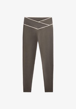 Högmidjade leggings i olivgrön med texturerad yta. Har ett kontrasterande ljusfärgat korsband vid midjan för extra detalj.