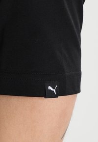 Svarta bomullsshorts med en slät textur, prydda med en liten vit Puma-logotyp vid kanten, vilket framhäver minimalistisk design.