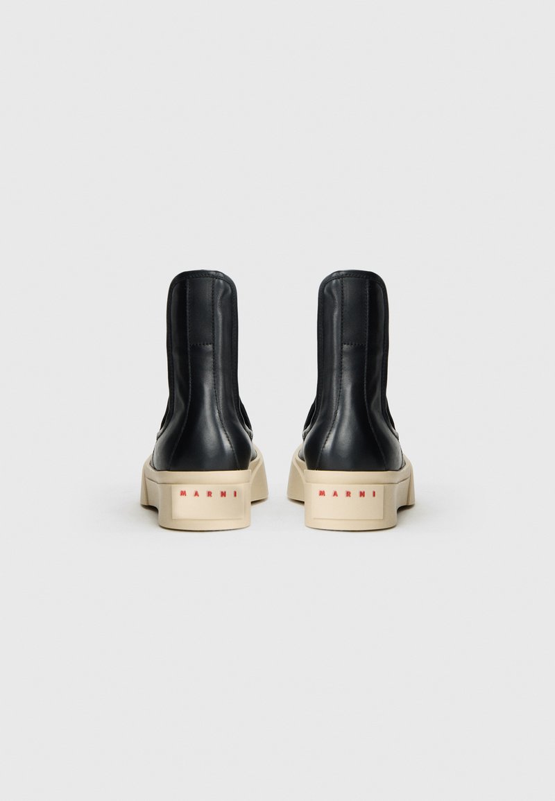 Stivaletti neri in pelle con finitura liscia, suola platform e base color crema con il marchio rosso "Marni" sul retro.