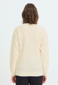 Hellbeige Strickpullover mit lockerer Passform, gerippter Struktur und langen Ärmeln, ausgestattet mit einem abgerundeten Ausschnitt und einem geraden Saum.