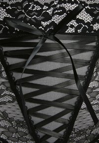 Schwarzes Spitzenkleid mit floralem Muster, verziert mit glatten Satinschleifen, die durch ein zentrales Panel gefädelt sind, und akzentuiert durch gewelltes Saumdesign.