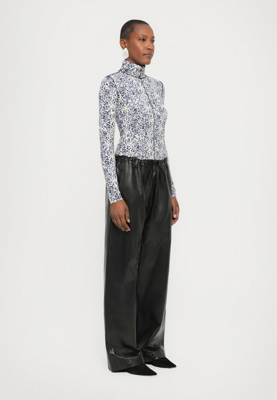 Fitted long-sleeve top with a floral pattern in blue and white; paired with black leather wide-leg pants and pointed black shoes.