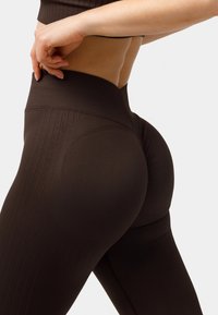 Hoch taillierte braune Leggings aus glattem Stoff, mit strukturiertem Rippenmuster und konturierten Nähten für einen verbesserten Sitz und eine optimale Form.