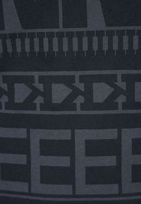 Mörkgrått tyg med djärv grafisk text och mönster i en ljusare nyans, med en slät textur och en figurnära design.