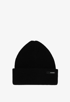 Zwarte gebreide beanie met een opgevouwen rand en subtiele geribbelde textuur. Heeft een klein logo-label aan de zijkant. Compacter ontwerp met een puntige bovenkant.