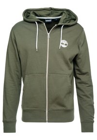 Sudadera con cremallera en verde oliva, hecha de material suave, con un bolsillo tipo canguro, cordones blancos y un logo en el lado izquierdo del pecho.