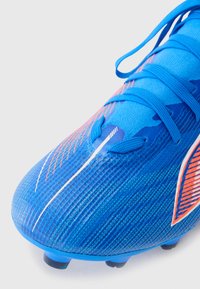 Blauer Fußballschuh aus strukturiertem Synthetikmaterial mit orangefarbenen Akzenten, kantigem Design und traditionellem Schnürverschluss.
