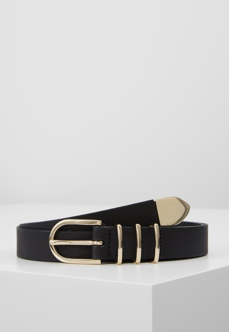 Ceinture en cuir noir avec boucle métallique dorée, trois passants dorés et une extrémité dorée, présentée sur une surface blanche sur un fond gris clair.