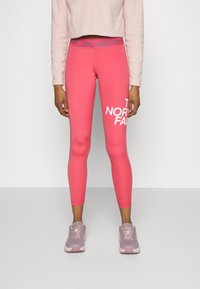 Rosa atletiska leggings med en åtsittande design, med en vit logotyp på vänster ben och en kontrasterande midjeband i blått och grått.