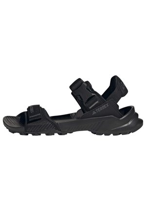 Sandales d'extérieur noires avec tige en synthétique, sangles ajustables, semelle intérieure texturée et semelle extérieure robuste pour une traction sur diverses surfaces.