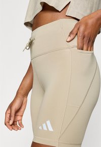 Μπεζ αθλητικό σορτς με ελαστικό υλικό, ψηλή μέση και πλαϊνή τσέπη. Διαθέτει λευκή επωνυμία στο κάτω αριστερό πόδι.