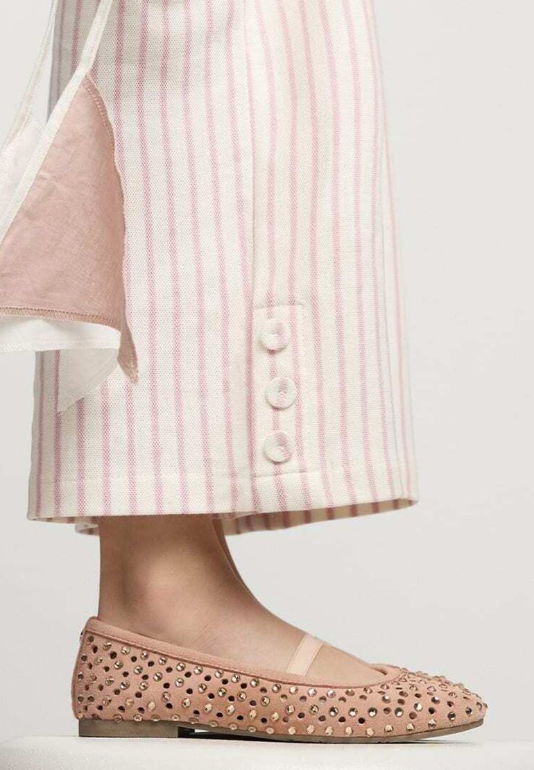Bailarinas color durazno con acentos texturizados, que presentan una punta redondeada y un diseño adornado. Tela ligera a rayas con botones en el dobladillo.