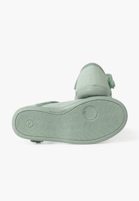 Grüne, strukturierte Schuhsohle mit Fischgrätmuster, featuring eine abgerundete Spitze und verstellbare Riemendetails im oberen Bereich.