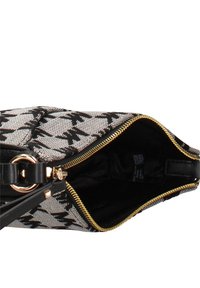 Borsa a tracolla con motivo bianco e nero, esterno in tessuto strutturato, cerniera dorata e tracolla in pelle nera con dettaglio circolare in metallo.