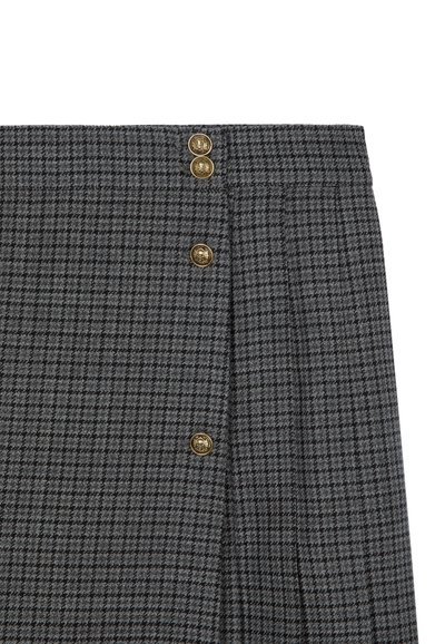Jupe à carreaux grise avec un design plissé, trois boutons dorés à la taille et une finition en tissu texturé.
