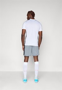 Halli hallid spordishortsid mustade külgaktsentidega, millele on kombineeritud valge lühikeste varrukatega jersei. Valged sokid ja akvamarinivärvi spordijalatsid, millel on "NIKE" bränd.