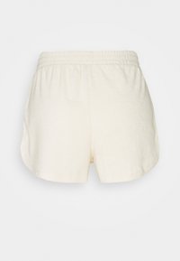 Krämfärgade shorts med en mjuk textur, utrustade med resårmidja och en avslappnad passform, formade med rundade fållar.