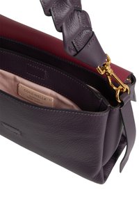 Borsa in pelle viola con accenti bordeaux, chiusura dorata, manico intrecciato e etichetta interna beige che riporta "Coccinelle Autentica Pelle Italiana."