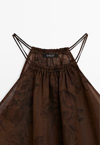 Bruine blouse van bloemenpatroonstof met een geplooide halslijn, verstelbare dunne bandjes en een label met "Massimo Dutti" aan de binnenzijde.