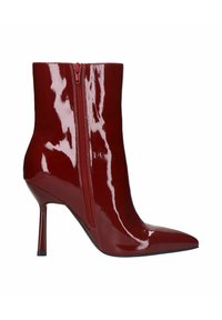Botte de cheville en cuir verni rouge avec un bout pointu et une fermeture éclair sur le côté, dotée d'un talon haut fin et d'une finition lisse et brillante.