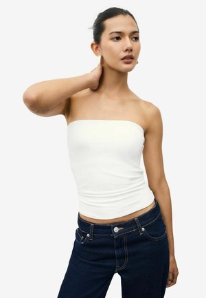 Balta strapless blouse, kas izgatavota no gludas materiāla. Pieguļošs dizains ar savilktu tekstūru jostasvietā. Savienota ar tumši ziliem džinsu biksēm.