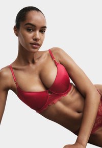 Rød blonde-bh med glatte skåle og en bølget kant. Justerbare stropper og et sømløst design forbedrer pasformen og støtten.