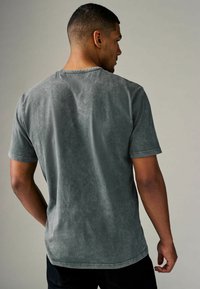 Gray, short-sleeved t-shirt made of soft fabric featuring a subtle texture, standard crew neck, and slightly curved hem at the back.