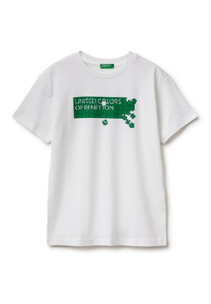 Wit T-shirt met een groen puzzelontwerp met de tekst "UNITED COLORS OF BENETTON", met aan de rechterkant enkele ontbrekende puzzelstukjes.