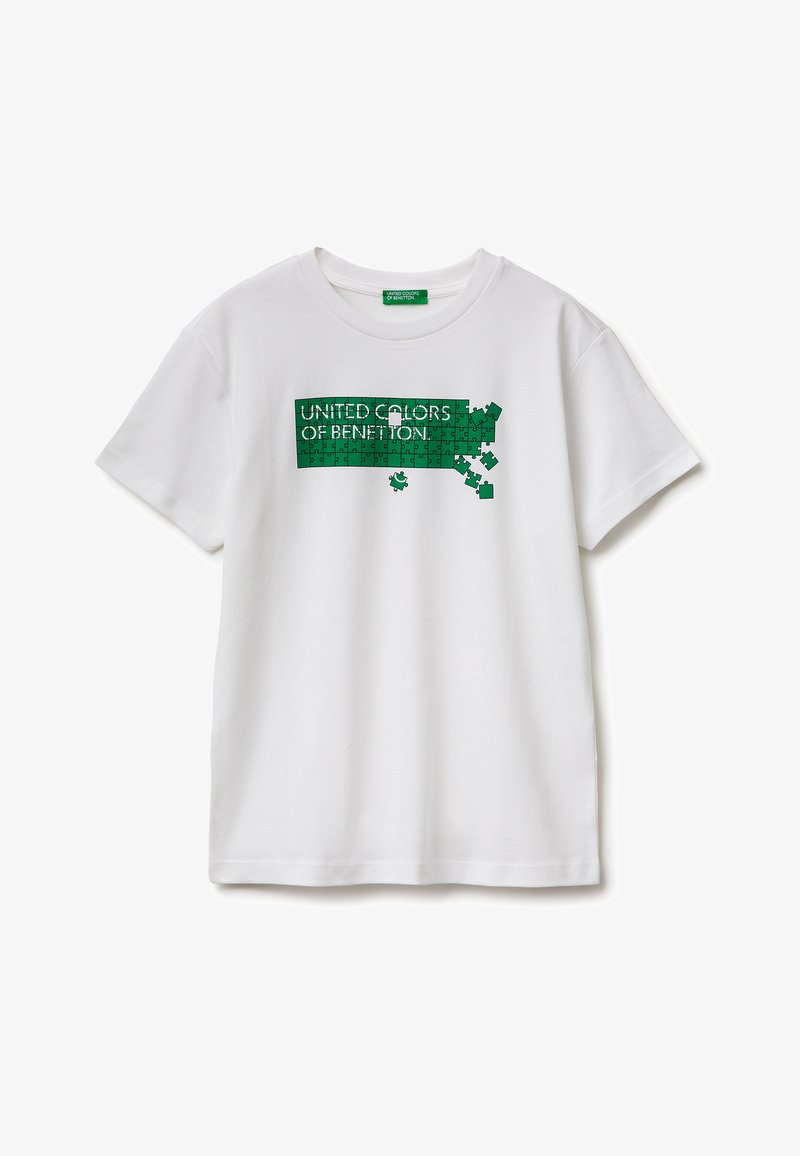 T-shirt blanc avec un motif puzzle vert formant l'inscription "UNITED COLORS OF BENETTON", plusieurs pièces du puzzle manquantes sur le côté droit.