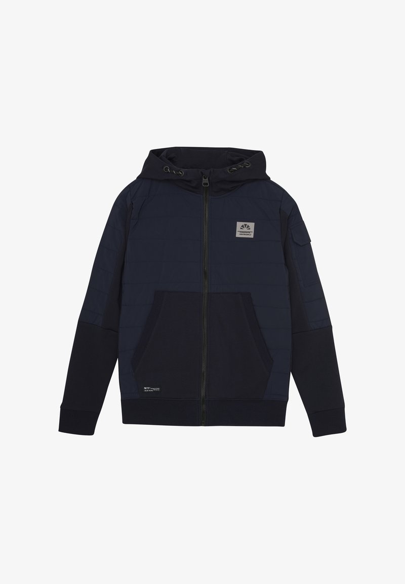 Marinblå huvjacka med vadderad textur, framsida med dragkedja, två fickor och en patchlogotyp på bröstet. Ribbad ärm- och midja.