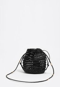 Mała czarna pleciona torebka ze ściągaczem, z długim plecionym paskiem i złotymi detalami na białym tle.
