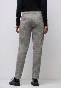Pantalons gris à motif chevrons avec une coupe ajustée, des jambes fuselées et une taille plate, assortis à des chaussures noires à lacets.