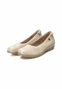Bailarinas beige con una parte superior de cuero sintético suave, punta redonda y un ligero tacón cuña. Acentuadas con botones decorativos en la parte trasera.