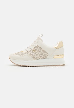 White sneaker with a textured upper, gold accents, patterned sides, and a cushioned sole. Features laces and a pull tab at the heel.