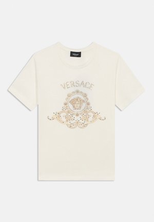 Valge lühikeste varrukatega T-särk Versace logoga, Medusa pea embleem ja kaunistatud kuldse dekoratiivse kujundusega ees.