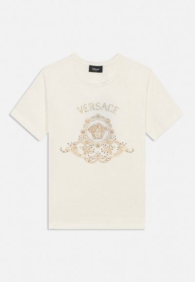 White short-sleeve T-shirt with Versace logo, Medusa head emblem, and ornate gold decorative design on front.