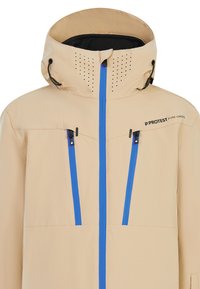Beige waterdichte jas met geperforeerde capuchon, blauwe ritsen en verstelbare toggles. Beschikt over twee zijzakken en logo detail.