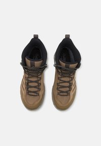 Bruine en zwarte wandelschoenen met een gestructureerde stof, versterkte neuskap en robuuste veters. Voorzien van een hoge kraag voor ondersteuning van de enkel.