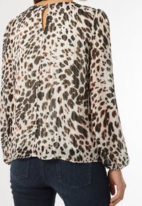 Blusa con stampa leopardata in tessuto leggero e plissettato. Presenta un colletto rotondo con apertura a chiave e maniche lunghe.