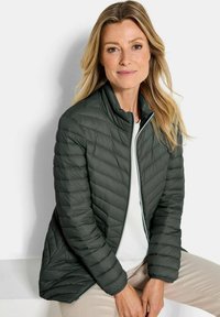 Donkergroene, gewatteerde pufferjack met een hoge kraag en ritssluiting, met een gladde textuur en een chevronpatroon in de vulling.