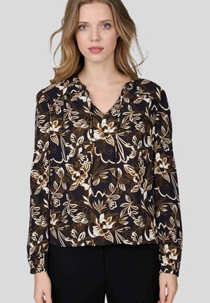 Blouse noire avec un motif floral agrémenté d'accents blancs et dorés, dotée d'un décolleté en V et de manches longues avec des poignets froncés.