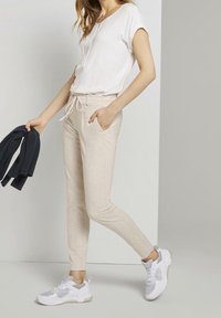 Krämfärgade joggers med dragsko i midjan, sidofickor, kombinerat med en vit topp och vita sneakers. Texturerad tyg, design med slim fit.