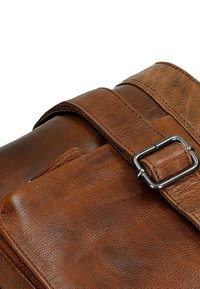 Sac messager en cuir marron avec une finition texturée, une bandoulière ajustable et une boucle métallique accentuée de détails de couture visibles.