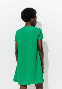Robe verte à manches courtes avec une coupe A-line décontractée, réalisée en tissu lisse, dotée d'une simple couture au dos et d'un col rond.