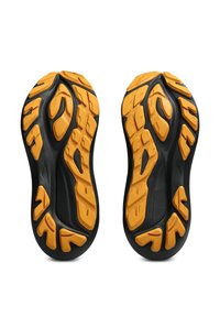 Schwarze Sportschuhsohlen mit einem strukturierten Muster; hervorgehobene gelbe Gummielemente verbessern den Halt und die Stabilität. Entwickelt für den Outdoor-Einsatz.