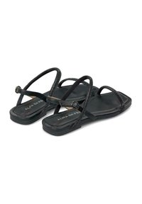 Czarne płaskie sandały z wieloma smukłymi paskami, okrągłym czubkiem oraz teksturowaną wkładką, z małym metalowym akcentem w postaci pierścienia.