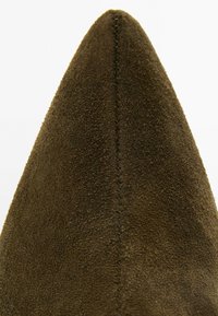 Scarpa in camoscio marrone punta a punta con una superficie testurizzata, caratterizzata da un dettaglio di cucitura ordinata lungo il bordo. Linee pulite e colore uniforme.